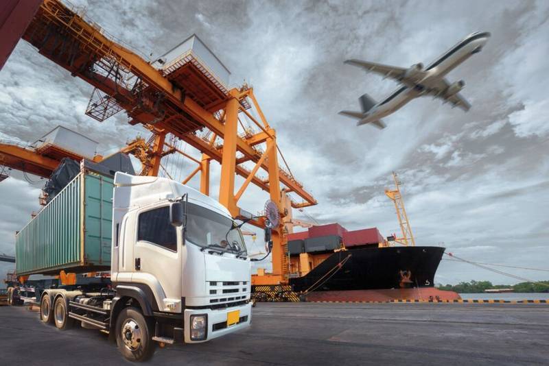 White truck with container, cargo ship, and airplane at a bustling port, representing Thai logistics and global supply chain.