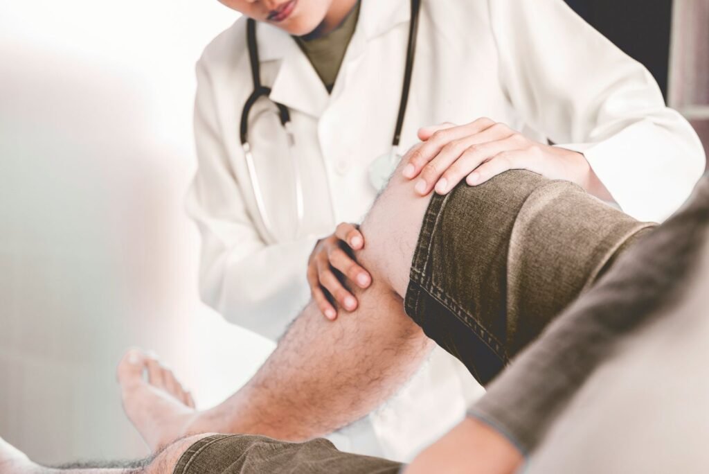 Physiotherapist in a white coat examines a patient's knee, representing specialized physiotherapy services for clinics.