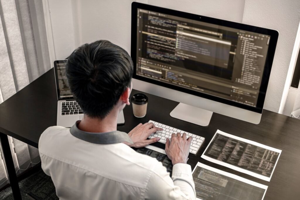 Expert developer actively coding on a large monitor, ensuring website security, optimization, and reliable maintenance.