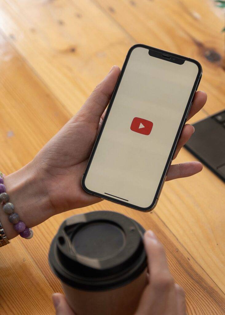 Person's hands hold a smartphone displaying the YouTube logo, symbolizing engaging video marketing and successful ad campaigns.