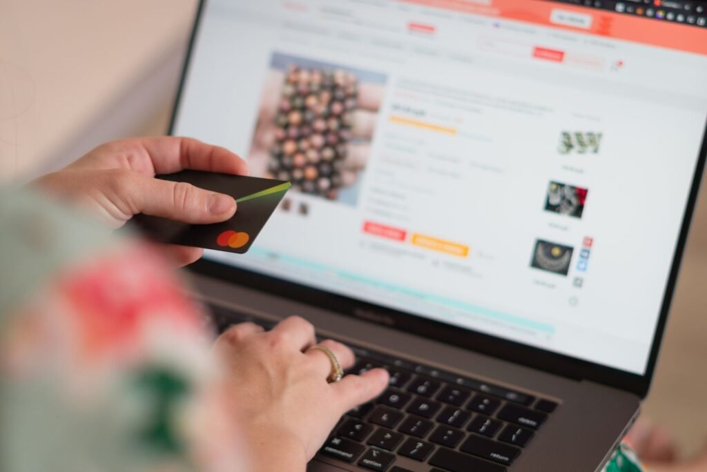 Hands holding a Mastercard credit card, typing on a laptop displaying an e-commerce site, driving online shopping conversions.