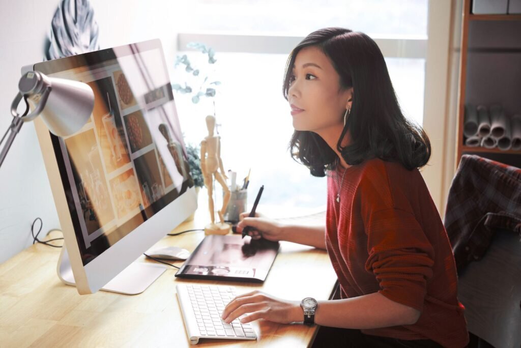 A female web designer in Bangkok meticulously crafting engaging website layouts on a computer with a graphics tablet.