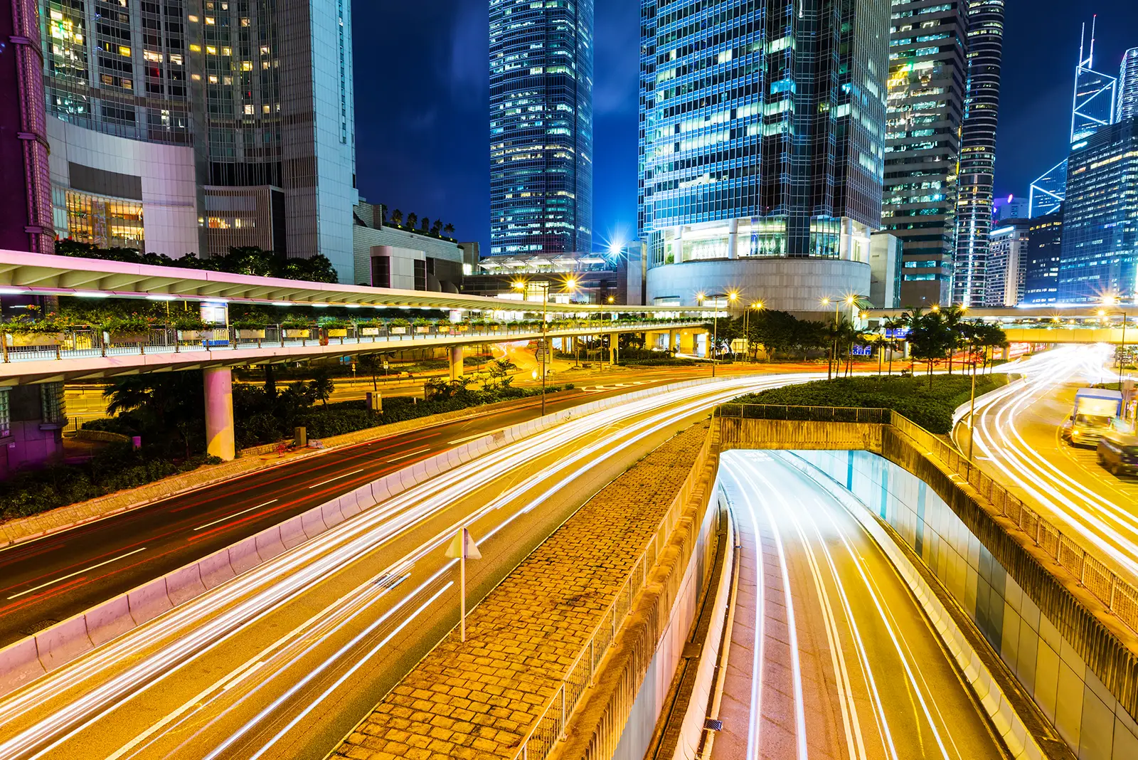 Dynamic cityscape at night with illuminated skyscrapers and streaking car lights on busy roads, reflecting digital growth.