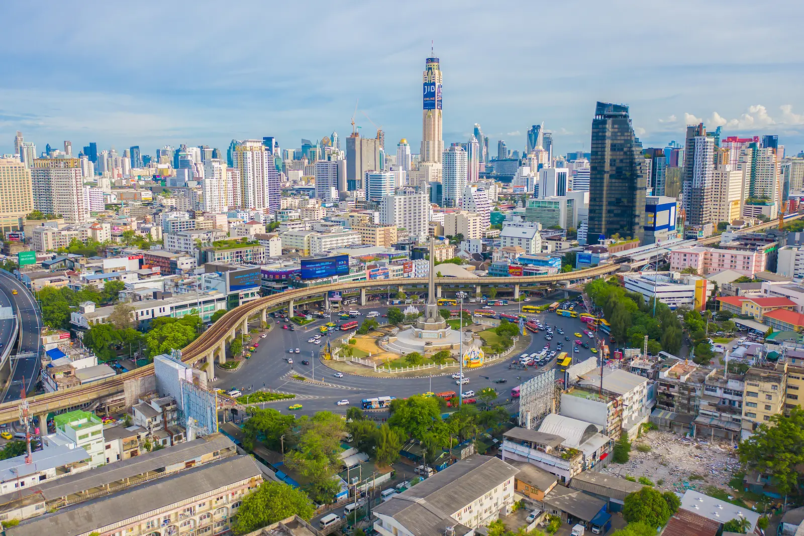 Bustling aerial view of Bangkok, showing Victory Monument roundabout, elevated train, and modern skyscrapers. Ideal market for digital marketing.