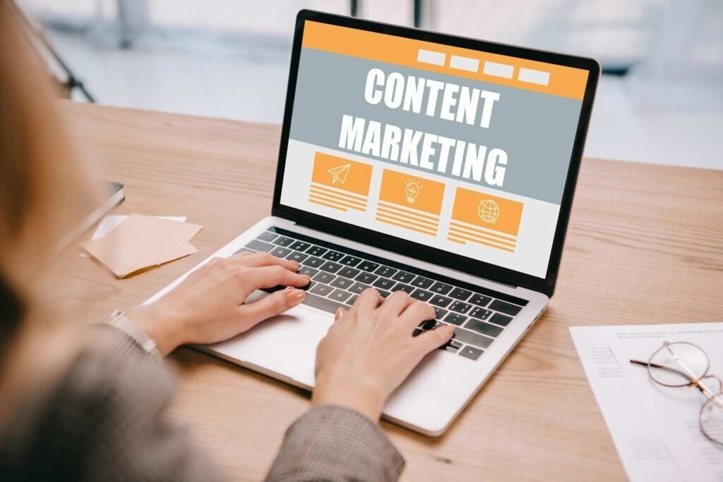 Hands typing on a laptop showing 'CONTENT MARKETING' with icons for strategy, ideas, and global reach, for our agency's services.