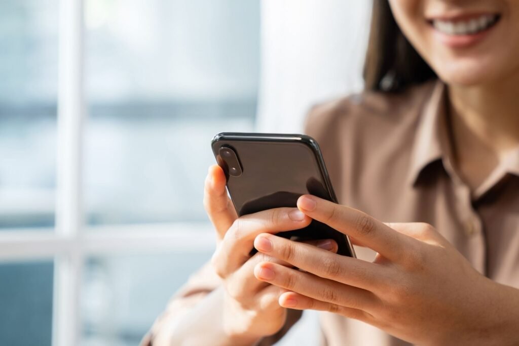 Smiling professional engaging with a smartphone, symbolizing digital reach and effective Google Performance Max campaigns.