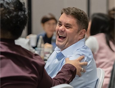 Male digital marketing expert in blue shirt laughing with a colleague, embodying Move Ahead Media's vibrant team and expertise.