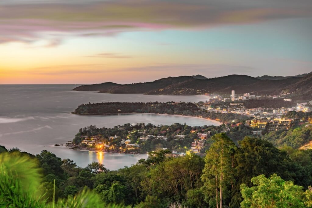 Phuket's vibrant coastal landscape at sunset, with illuminated buildings, bays, and lush hills, representing a thriving digital marketing hub.