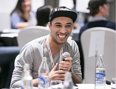 Smiling Move Ahead Media digital marketing expert in a cap, holding a microphone, actively engaging at a professional event.