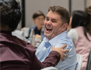 Male digital marketing expert in blue shirt laughing with a colleague, embodying Move Ahead Media's vibrant team and expertise.