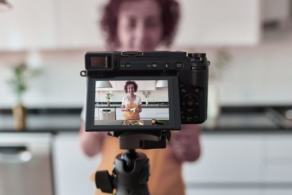 Camera screen displays a smiling woman in an apron chopping vegetables, representing engaging content creation for your brand.