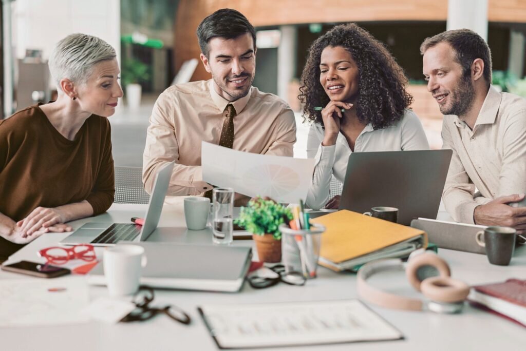 Diverse team of CRO experts analyzing data and strategy on laptops, collaborating to boost client conversion rates.