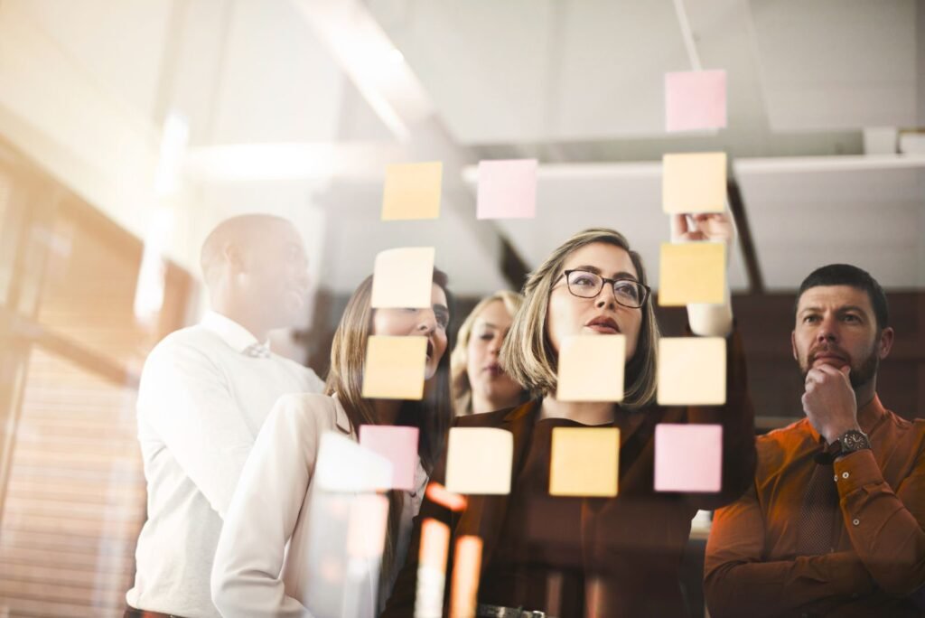 Diverse team collaborating, arranging sticky notes on a glass board, strategizing data-driven CRO for marketing campaigns.