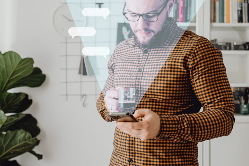 Man in glasses and plaid shirt intently viewing his smartphone, with digital speech bubbles representing effective email campaign engagement.