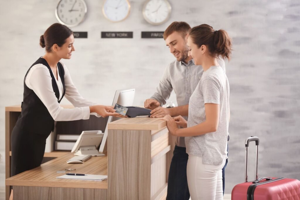 Hotel receptionist assists a smiling couple with credit card payment at check-in, showcasing hospitality engagement.