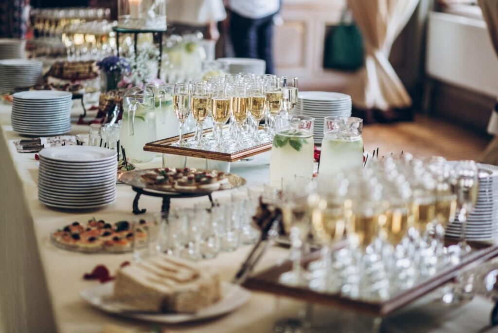 A lavish buffet table featuring sparkling wine flutes, refreshing lemonade, gourmet appetizers, and elegant cake slices.