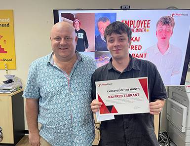 Move Ahead Media's Kai Tarrant, Employee of the Month, receives his award from a smiling colleague, highlighting our expert team.