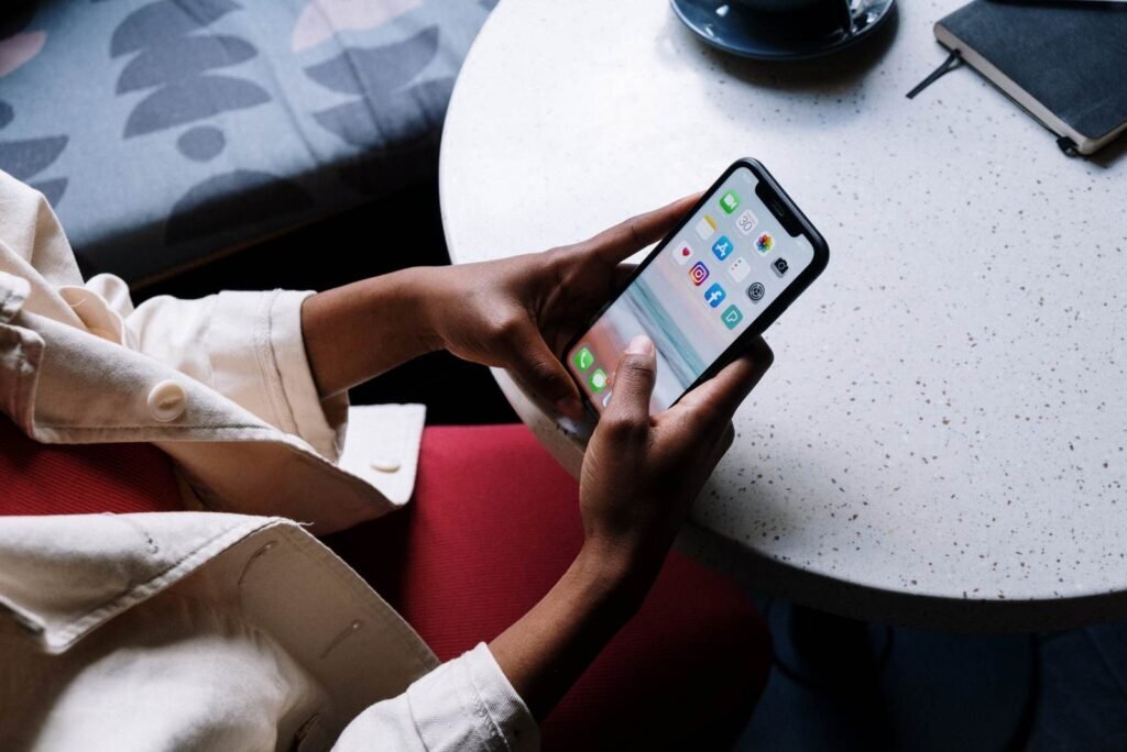 Hands holding a smartphone showing Facebook and other social media apps, crucial for Facebook lead generation.