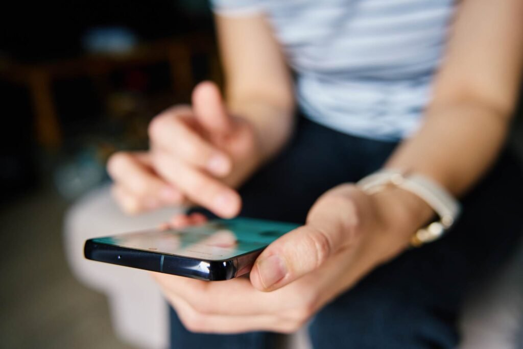 A person's hands actively tapping a smartphone screen, demonstrating engagement with Facebook lead generation ads.