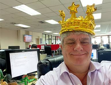 Smiling Move Ahead Media team member, a digital marketing expert, proudly wears a gold inflatable crown in the office.