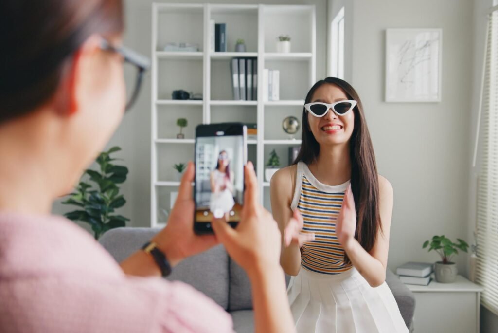 Two women creating engaging, scroll-stopping TikTok content. One records a smiling woman in stylish cat-eye sunglasses.