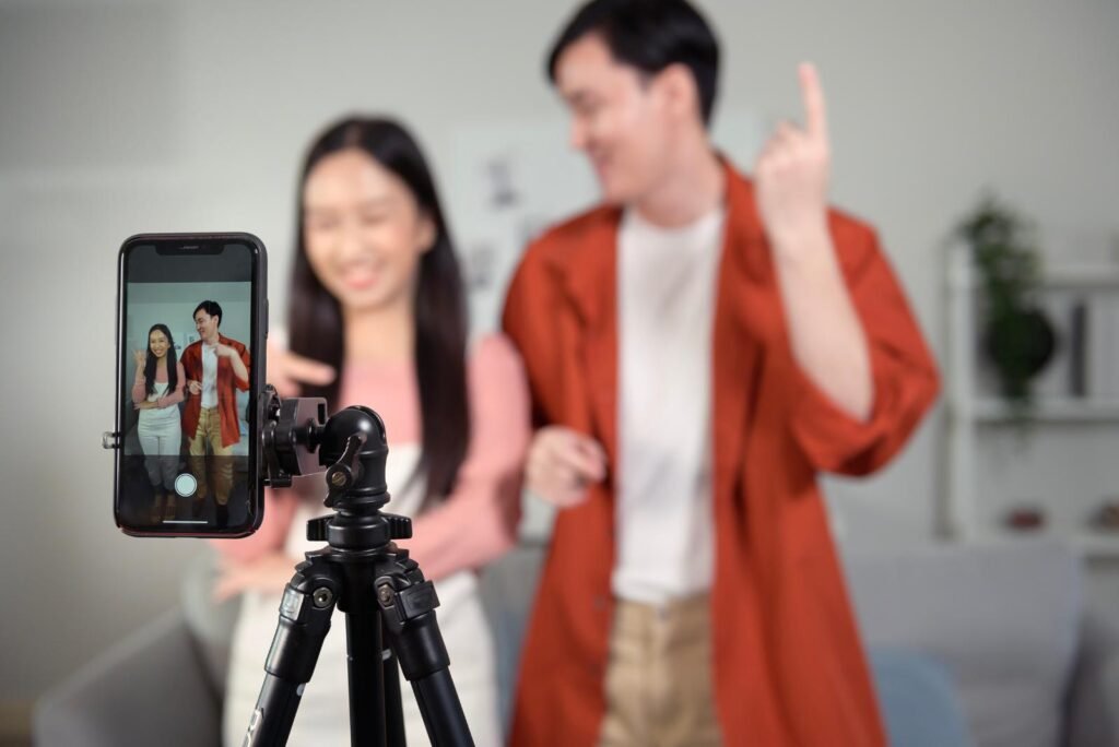 Two smiling content creators film a vibrant TikTok video on a smartphone and tripod, ideal for scroll-stopping ad campaigns.