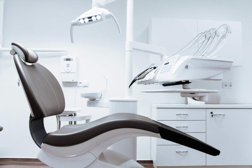 Clean, modern dental practice exam room with a grey patient chair, bright light, and advanced equipment.