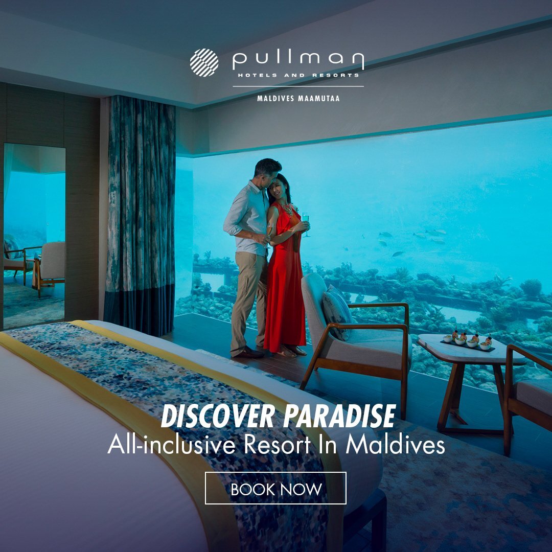 Couple in a luxury underwater hotel room with a vibrant coral reef view, showcasing aspirational hospitality marketing.