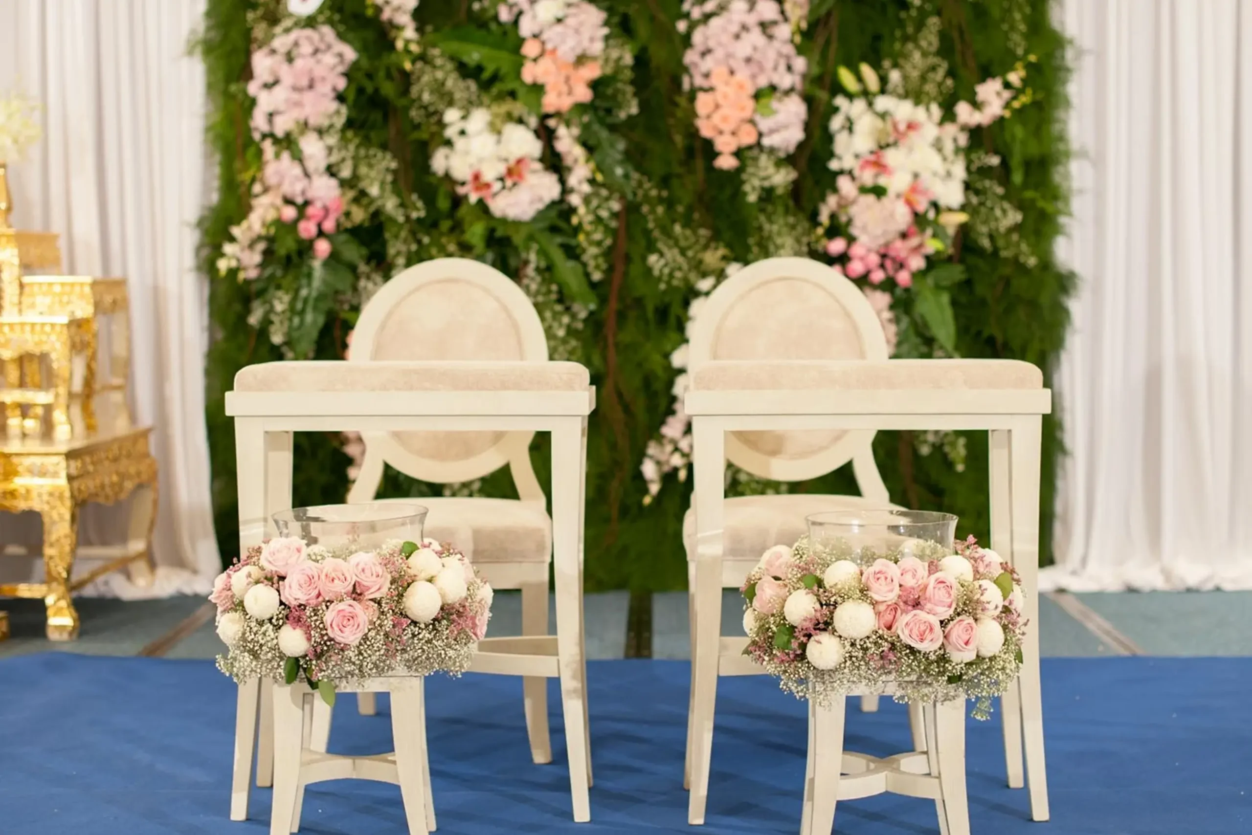 Elegant event setup for hotels or resorts in Thailand, featuring two white chairs, pink rose arrangements, and a lush flower wall.