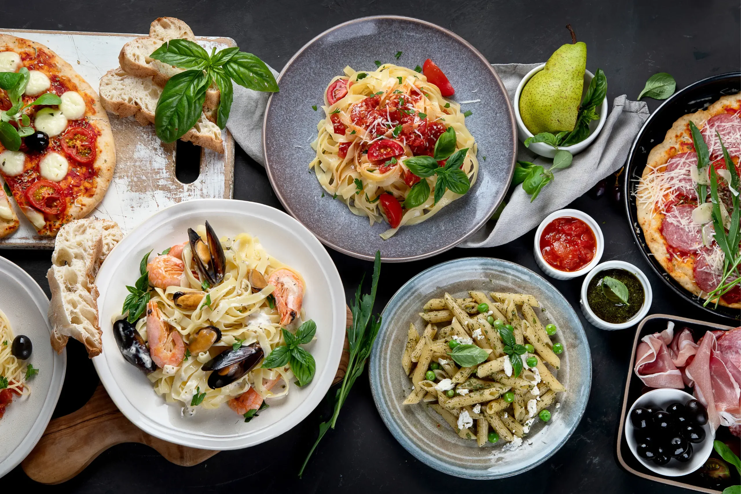Diverse Italian cuisine spread with pasta, pizzas, and charcuterie, highlighting restaurant and hotel dining.